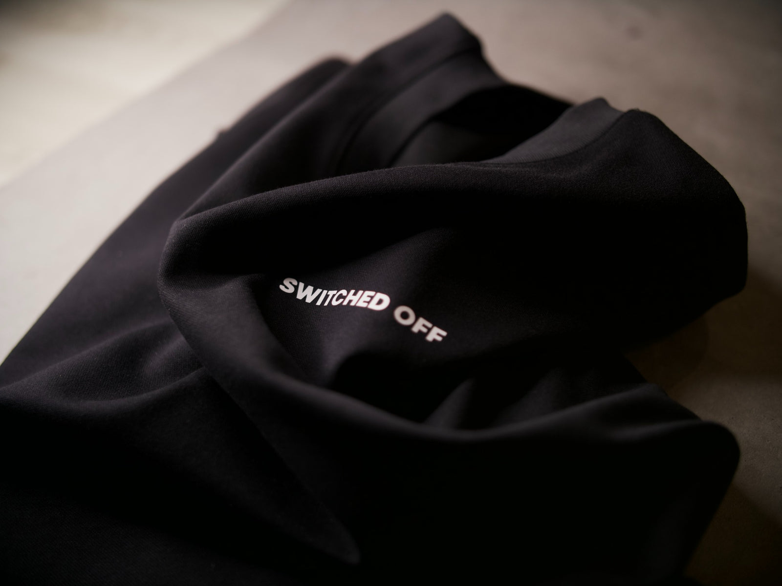 Close-up of black SWITCHED OFF clothing and white wordmark