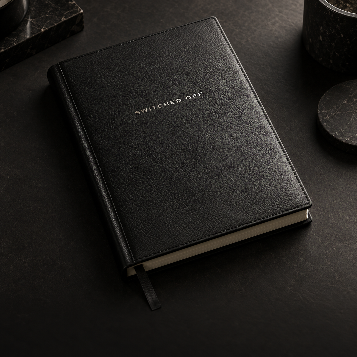 Black leather SWITCHED OFF journal in a dark setting